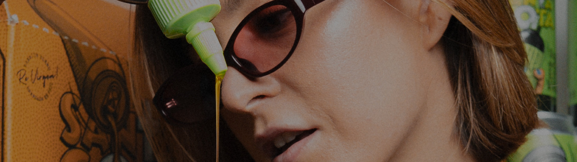 Mujer con gafas de sol mientras cae un hilo de aceite de oliva desde un squeeze Santa Gota